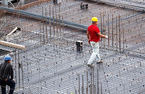 Obra civil com armação estrutural e trabalhadores